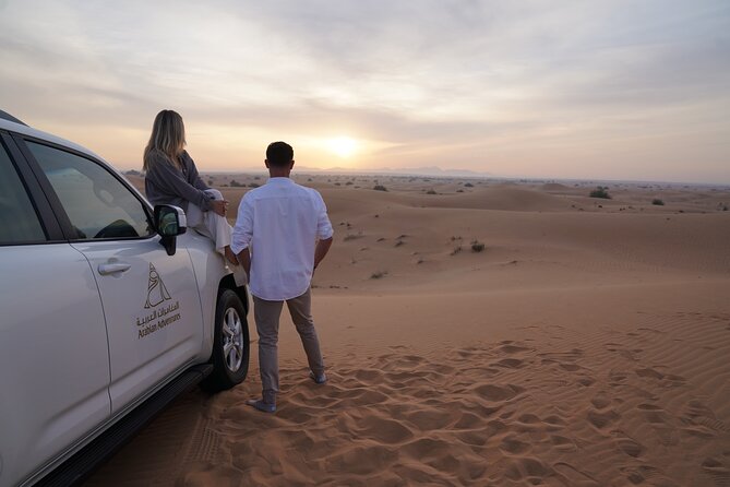 Dubai Evening Desert Safari: Sandboarding, BBQ, Camel Ride & more - Sunset with soft drinks and open desert views